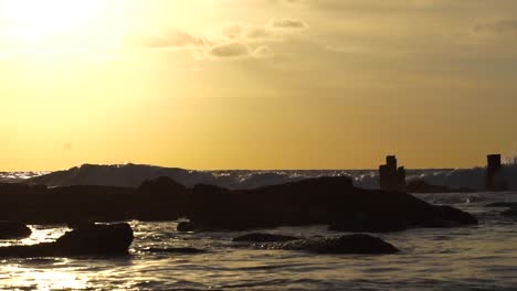 sunset on sea while the waves hit rocks