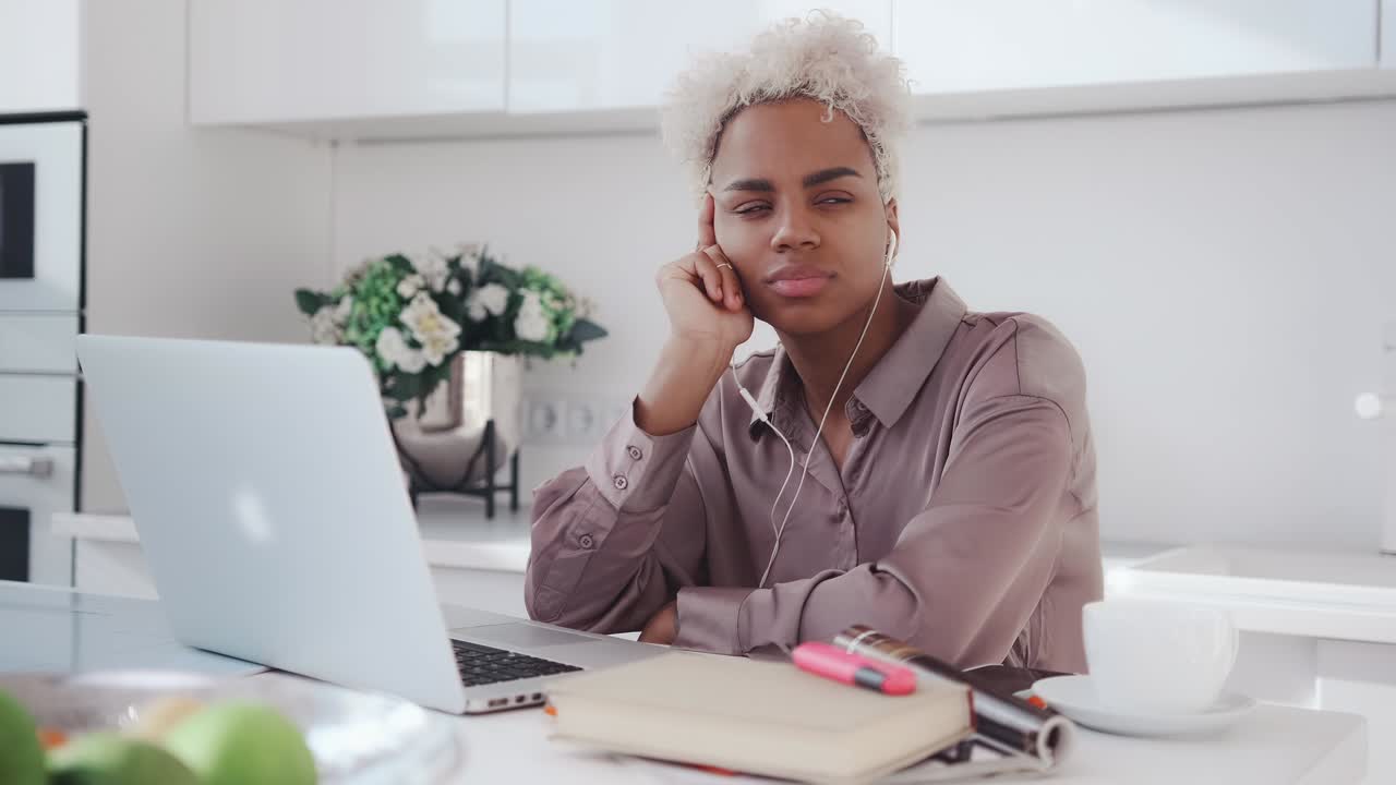 Ung afroamerikansk kvindelig freelancer med høretelefoner taster på sin laptop.