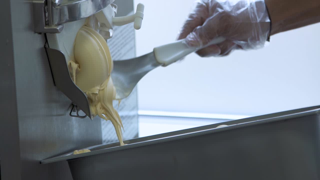 el fabricante de gelato extrude postre cremoso, cucharas de mano en un recipiente de metal