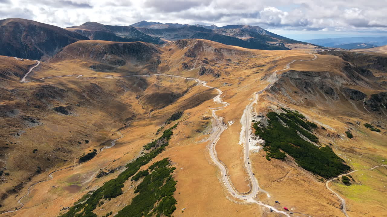Aerial drone view of nature in Romania. Carpathian mountains, sparse vegetation, Transalpina road with cars
