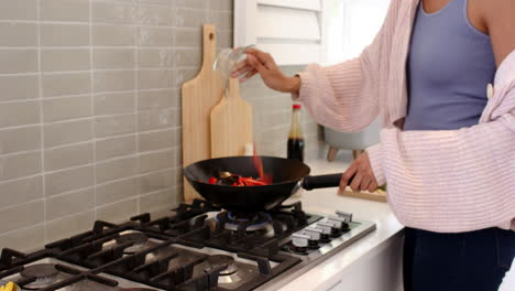 woman cooking on stove in cozy kitchen, wearing warm sweater