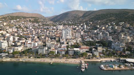 Aerial-Sliding-Shot-Reveals-Saranda,-Albania-Coastline-on-Typical-Summer-Day