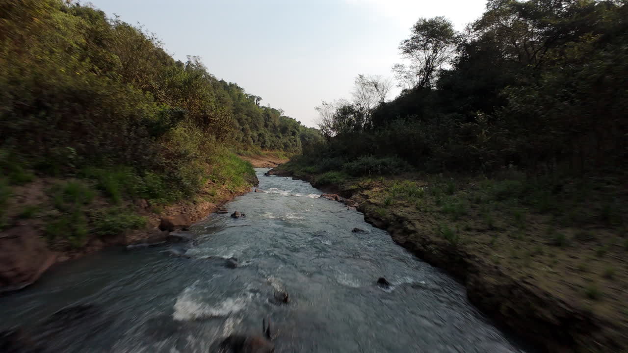 Scenic fpv aerial of Salto Yasi waterfall flowing through a dense green forest in Misiones, Argentina, shaded water river