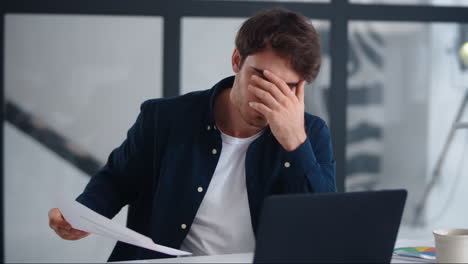 Upset-businessman-finding-mistakes-in-documents.-Sad-guy-looking-papers-indoor