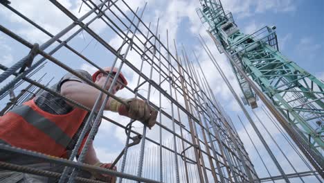 a worker uses steel tying wire to fasten steel rods to reinforcement bars. reinforced concrete structures - knitting of a metal reinforcing cage.