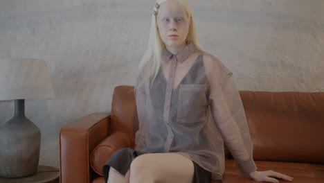 blonde woman in fashionable outfit on a sofa