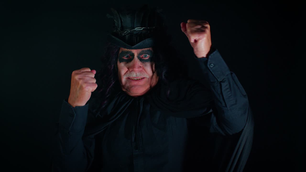 Un uomo anziano (nonno) dall'aspetto inquietante con un trucco da stregone di Halloween alla moda celebra la vittoria, si rallegra e dice "Sì".