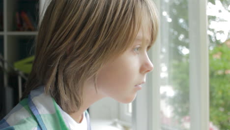 young boy walking into frame and looking out of his bedroom window