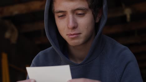 a young teen boy sits in a garage wearing a hoodie