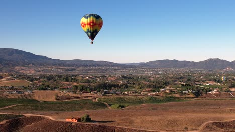 Colorido-Globo-Aerostático-Volando-Sobre-El-Valle-Soleado-Y-La-Pequeña-Ciudad-En-El-Campo-De-California,-Ee