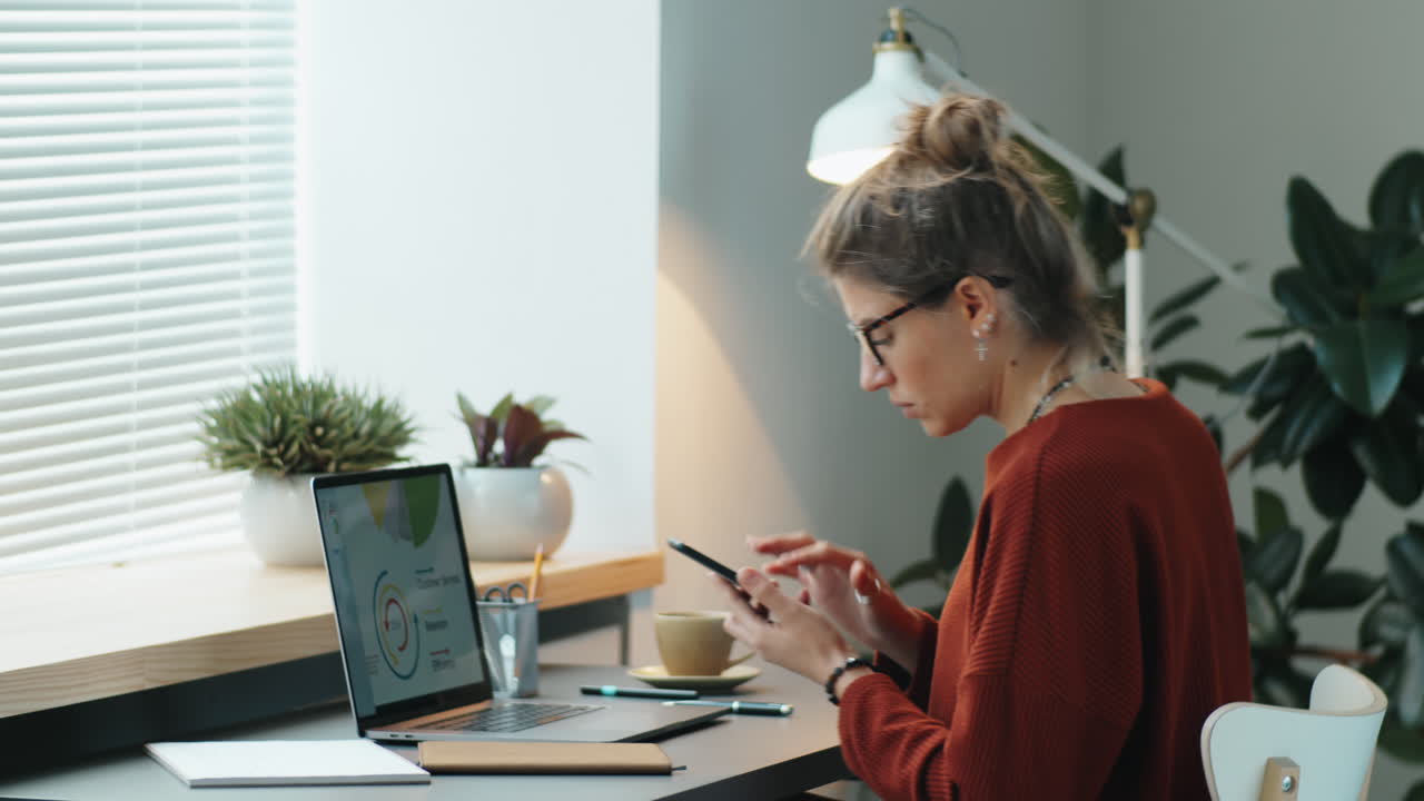 Giovane donna che usa smartphone e laptop in ufficio