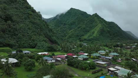 rainy rain clouds teahupoo tahiti french polynesia aerial drone fog morning grey gray raining season wet green grass end of the road point faremahora village town buildings mountains island upward