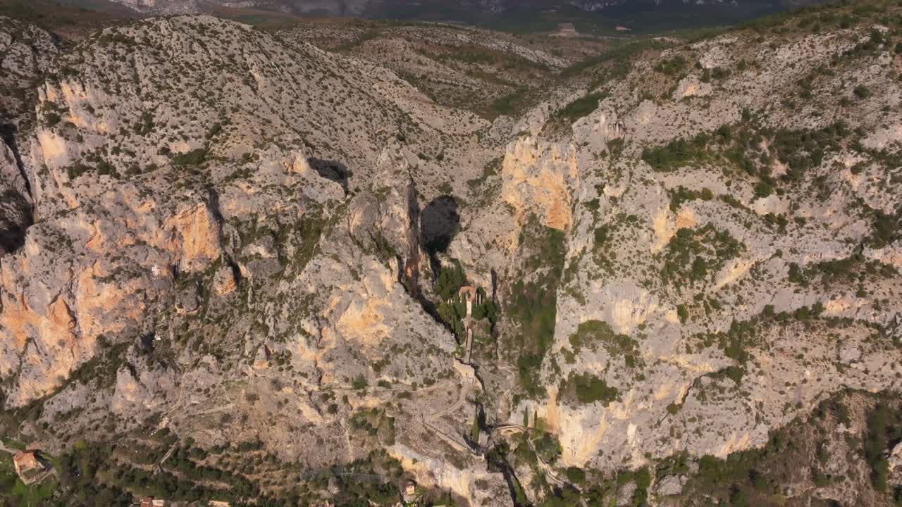 Vista aerea di un borgo collinare francese adagiato su terrazze rocciose in Alta Provenza.