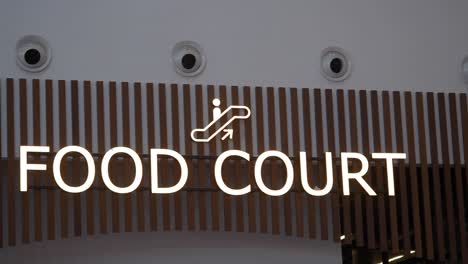 illuminated "food court" sign with escalator icon
