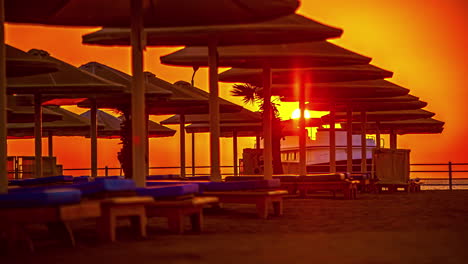 sun umbrella and empty deckchairs at sunset with boat arriving and departing in background