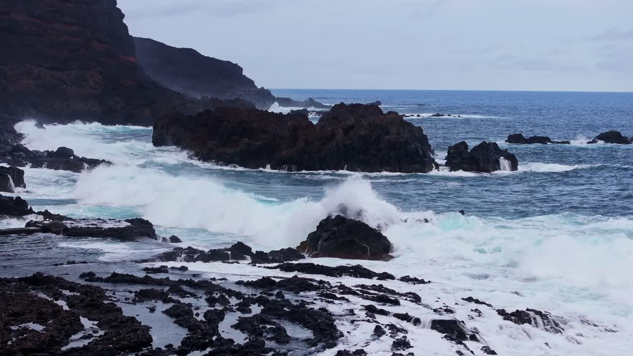 Powerful waves hit dark volcanic coast just before sunrise in El Hierro, Spain