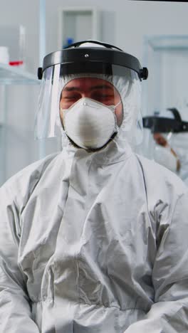 vertical video: portrait of experienced scientist man in coverall smiling at camera