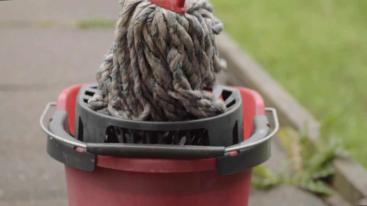 escurrir el trapeador de limpieza en un cubo rojo plano general