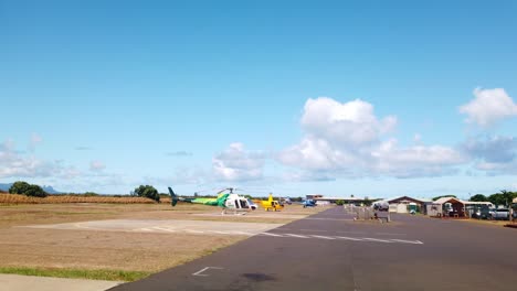 Gimbal-wide-booming-down-shot-of-helicopters-lined-up-on-the-tarmac-at-a-heliport-on-the-island-of-Kaua'i,-Hawai'i