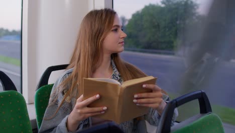 young woman reading a book on the bus