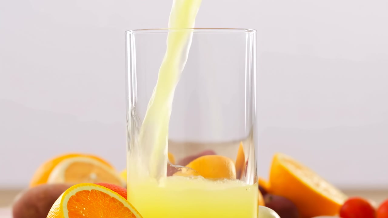 Succo d'arancia fresco versato in un bicchiere, scena di cucina casalinga con vivaci spicchi di agrumi e polpa giallo pallido.