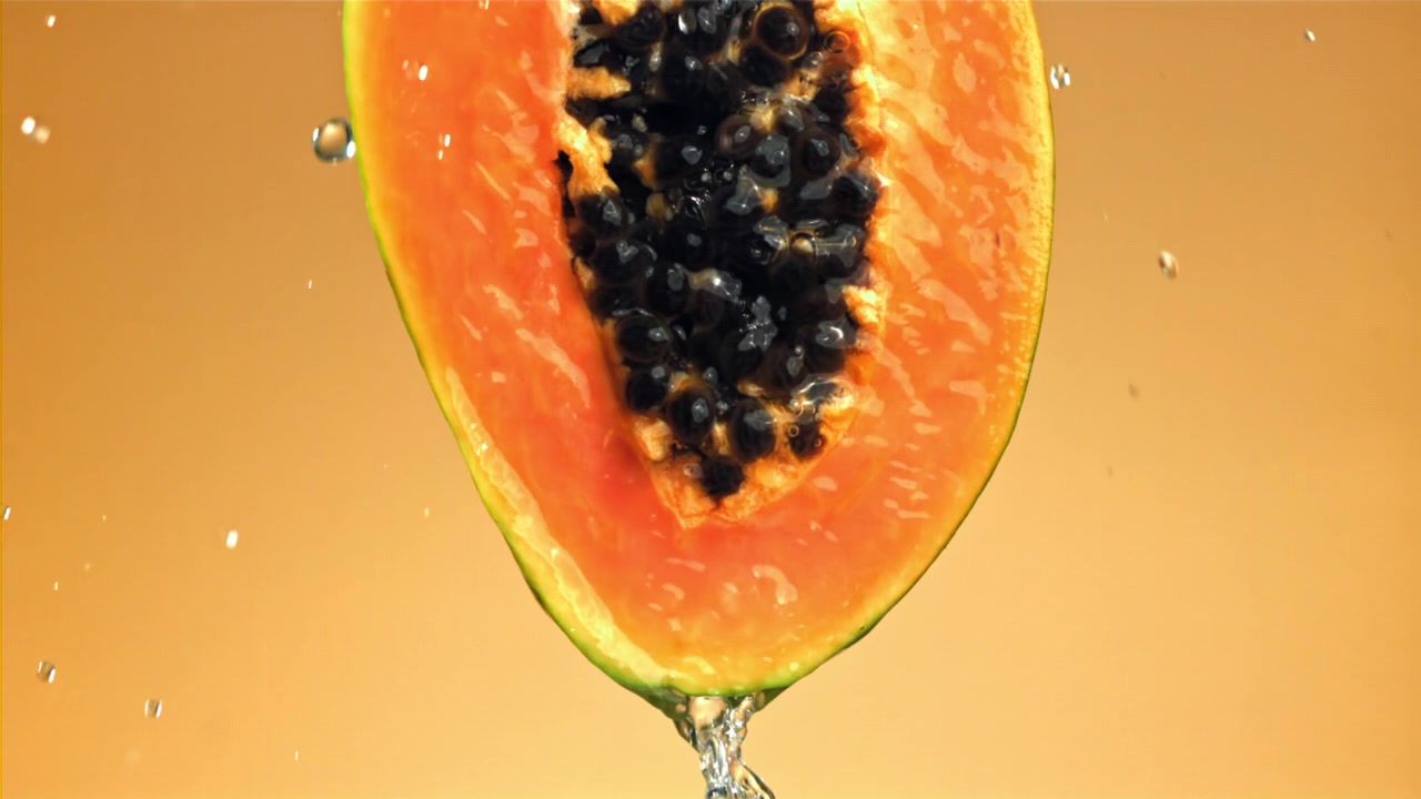 Schizzi d'acqua al rallentatore su una metà di papaya arancione vivace