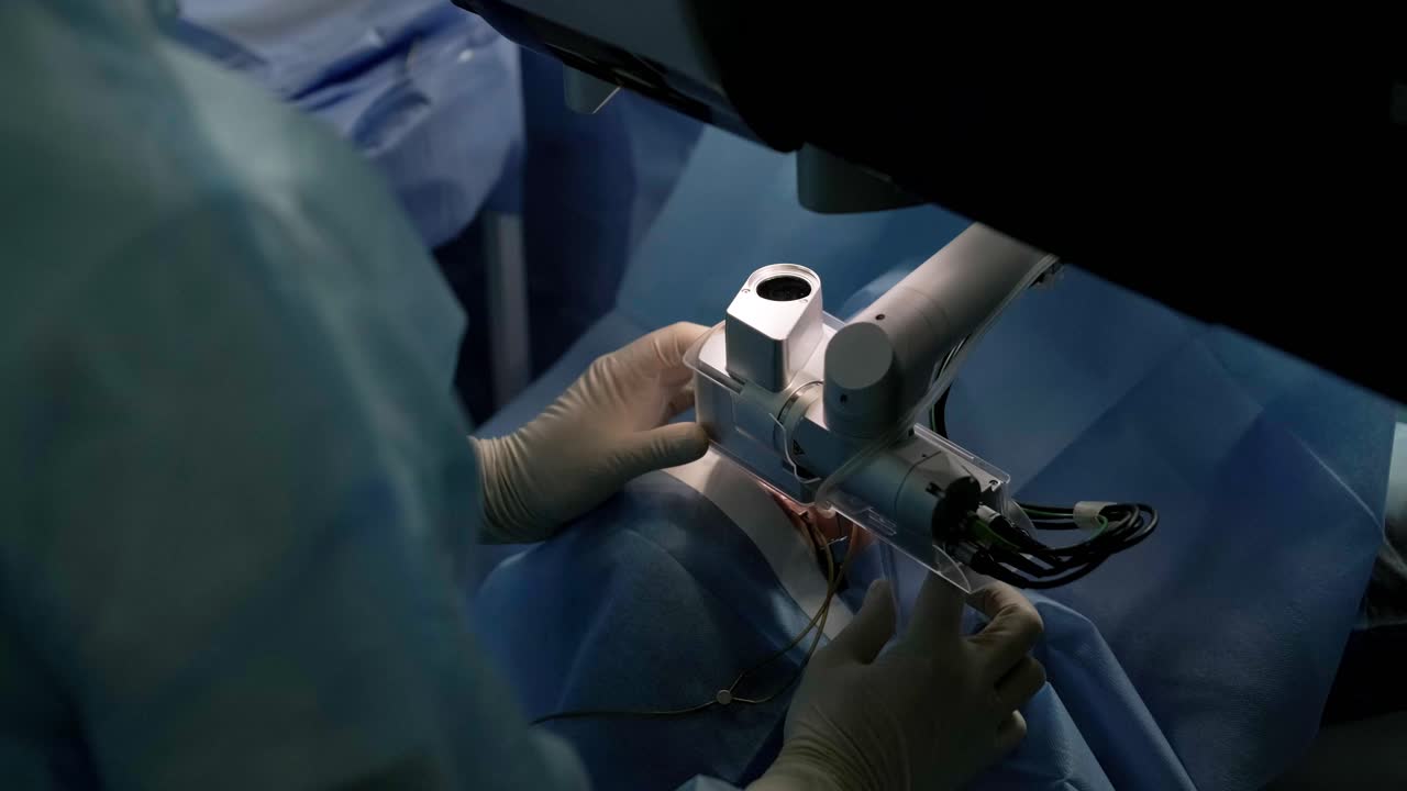 안과 수술 전문가가 현미경 앞에 앉아서 수술을 하고 있습니다.