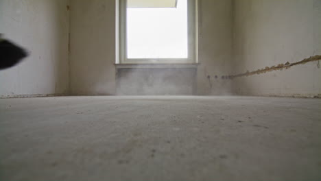 wide shot of sweeping on a dusty floor with and old broom