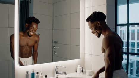 man smiling while applying skincare in the bathroom