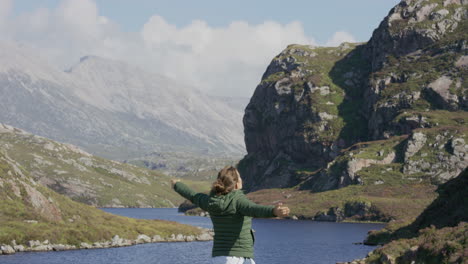 young woman arms raised happy tourist enjoying beautiful scenic landscape on successful travel vacation exploring relaxing outdoors lifestyle