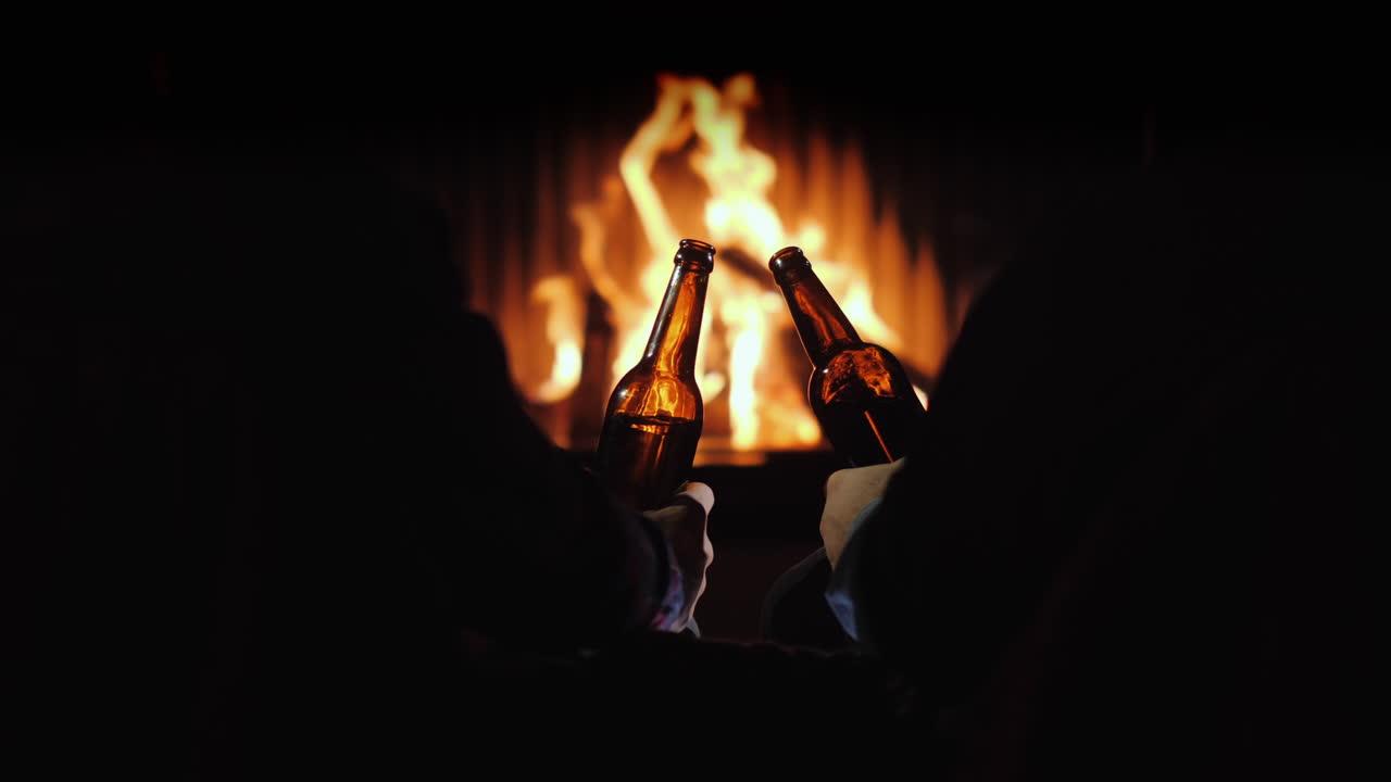 dos hombres descansan con botellas de cerveza en la mano junto a la chimenea y decoraciones navideñas