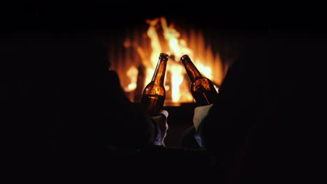 two men rest with bottles of beer in hand by the fireplace and christmas decorations