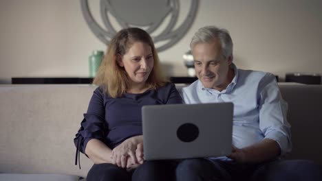 pareja adulta positiva que usa una computadora portátil para una videollamada