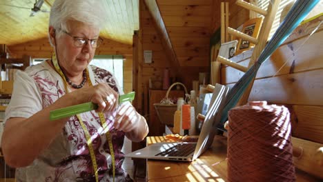 vista lateral de una anciana mujer caucásica trabajando en una computadora portátil en un taller 4k