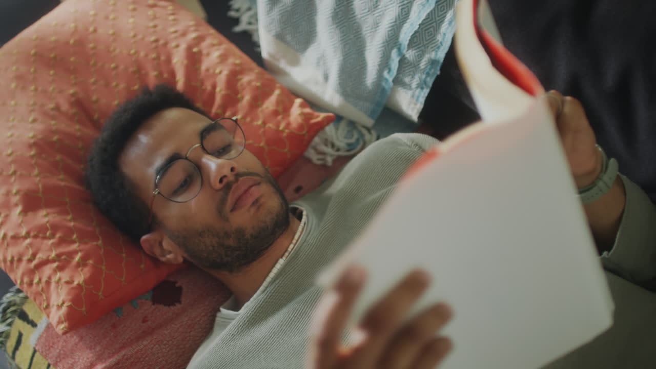 Young Man Reading Book on Sofa