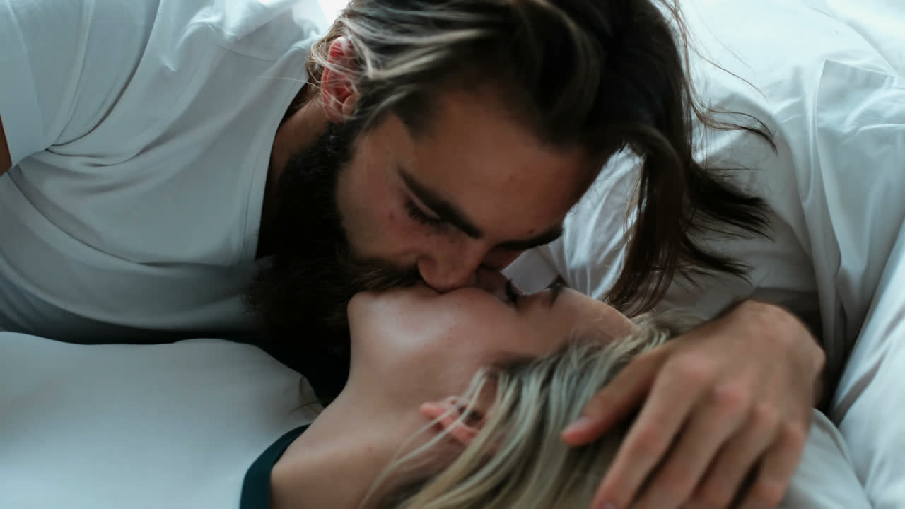pareja besándose en la cama en el dormitorio 4k