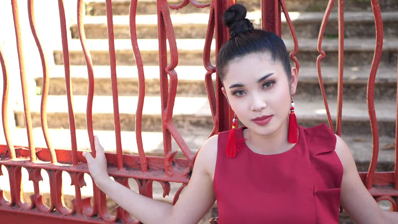 Beautiful Asian Woman In Red Suit Pose At Red Metal Fence , Slow Motion