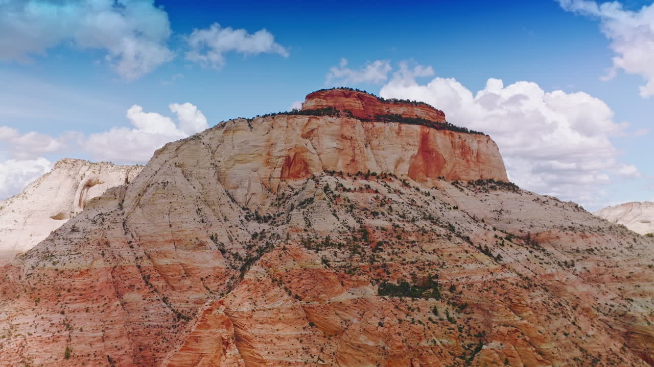 Wonderful huge rock with flat top and little greenery on. Amazing canyon of Zion National Park in Utah, USA at the backdrop of blue sky with white clouds.