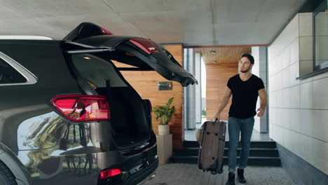 Caucasian-man-loading-suitcase-in-black-car-in-luxury-garage.