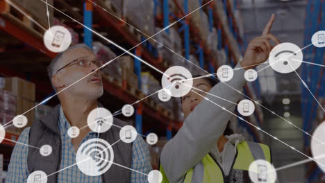 animation of network of connections with icons over diverse people working in warehouse