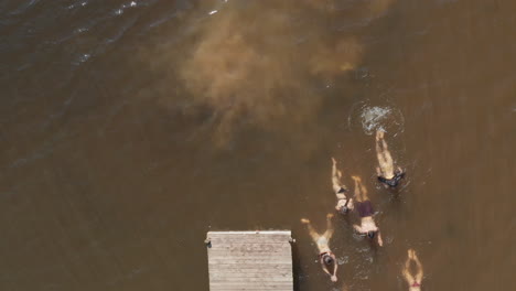 aerial-view-friends-swimming-in-lake-having-fun-splashing-in-water-enjoying-summer-vacation-overhead-drone-view-from-above