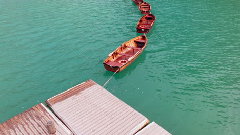aerial closeup reveals lago di braies wooden rowing boats and surrounding, lake braies within the fanes-sennes-braies nature park, dolomites