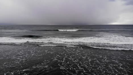 Drone-flying-out-towards-man-catching-a-wave-and-surfing-in