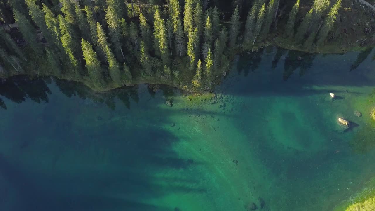 полет дрона в обратном направлении при наклоне камеры вверх над озером карецца в доломитовых альпах, италия в 4k