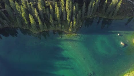 droneshot-flying-backwards-while-tilting-the-camera-up-over-Lake-Carezza-in-the-Dolomites,-Italy-in-4k