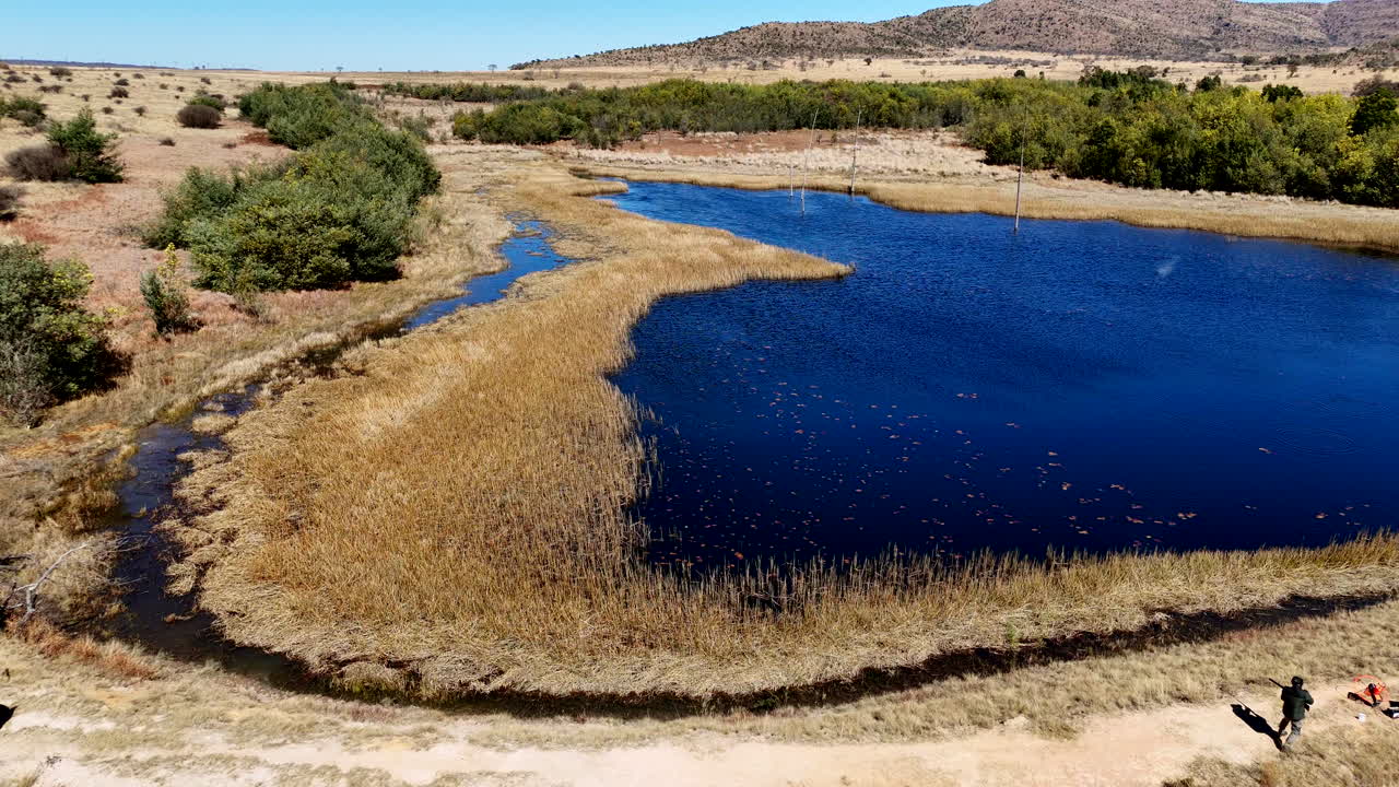 Drone view of man on dam wall shooting clay pigeon from catapult into pieces