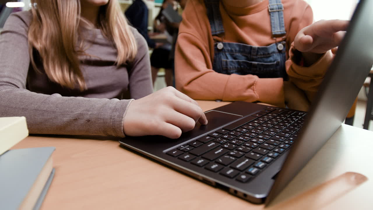 Students collaborate on a laptop in a library setting