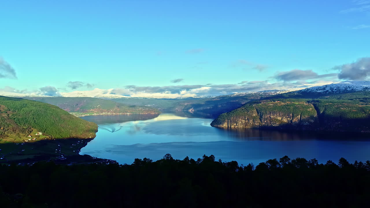 lago attersee en austria con un pueblo a lo largo de la orilla - volando a través de los árboles