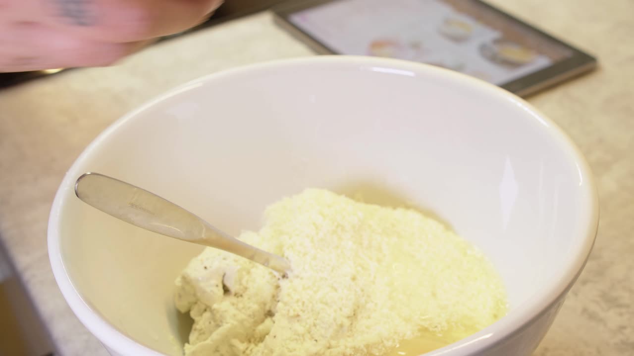 Raw egg is added to ingredient bowl while making cheesecake filling