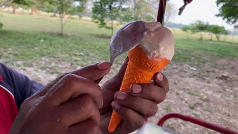 cierre la mano del personal masculino con cuidado preparando hielo cubierto de nieve del carro de helado de vainilla al aire libre